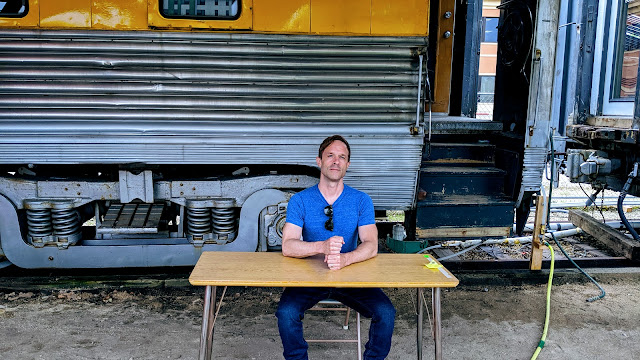 Tom Ray sitting at a table in front of a Train